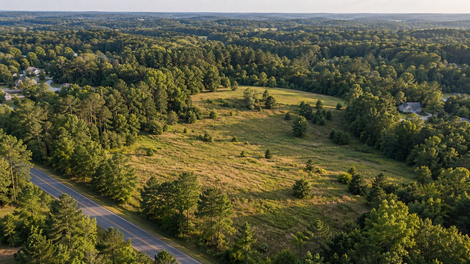 Illustrative aerial view of rolling land, woodland and a two-lane road in a Charlotte-area setting